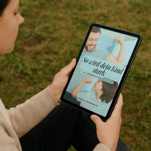 KI-generierte Frau, die ein Tablet in der Hand hält auf dem sie das E-Book "So wird dein Kind stark" steht.